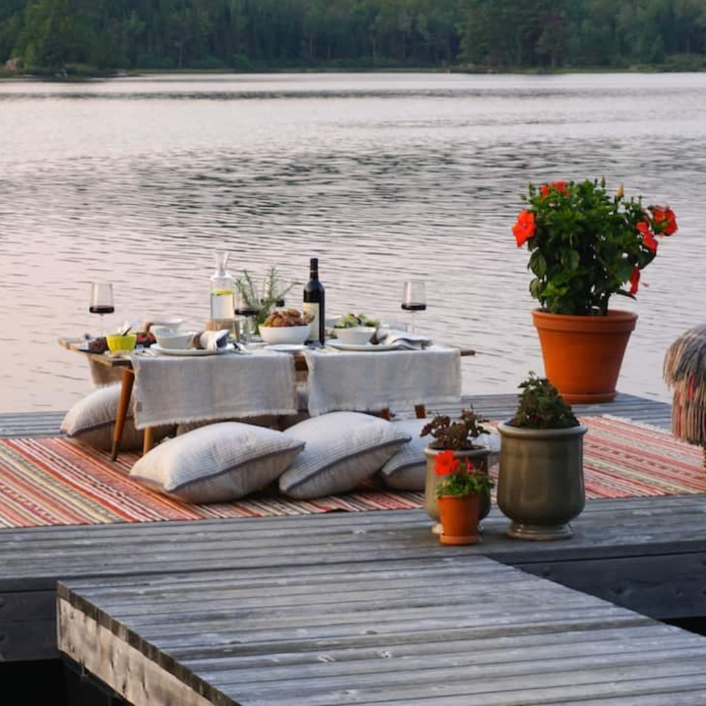 A beautiful table setting surrounded by potted plants on a dock by a serene lake