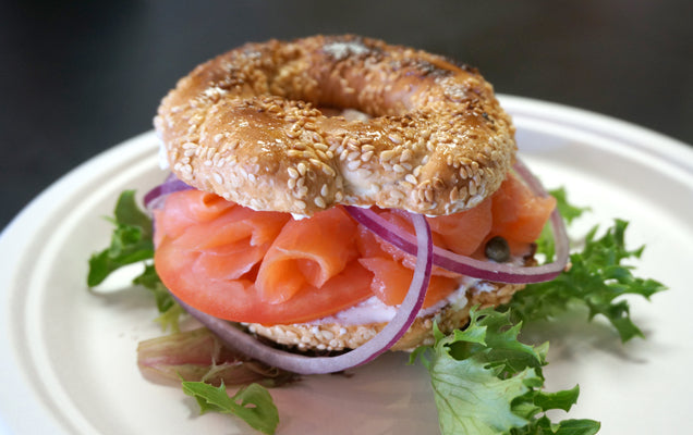 Sliced Bagel and lox with salmon and cream cheese on a white plate