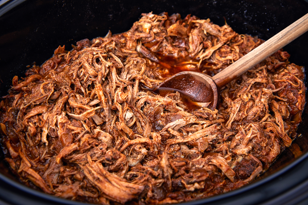 Braised pulled pork with a wooden serving spoon