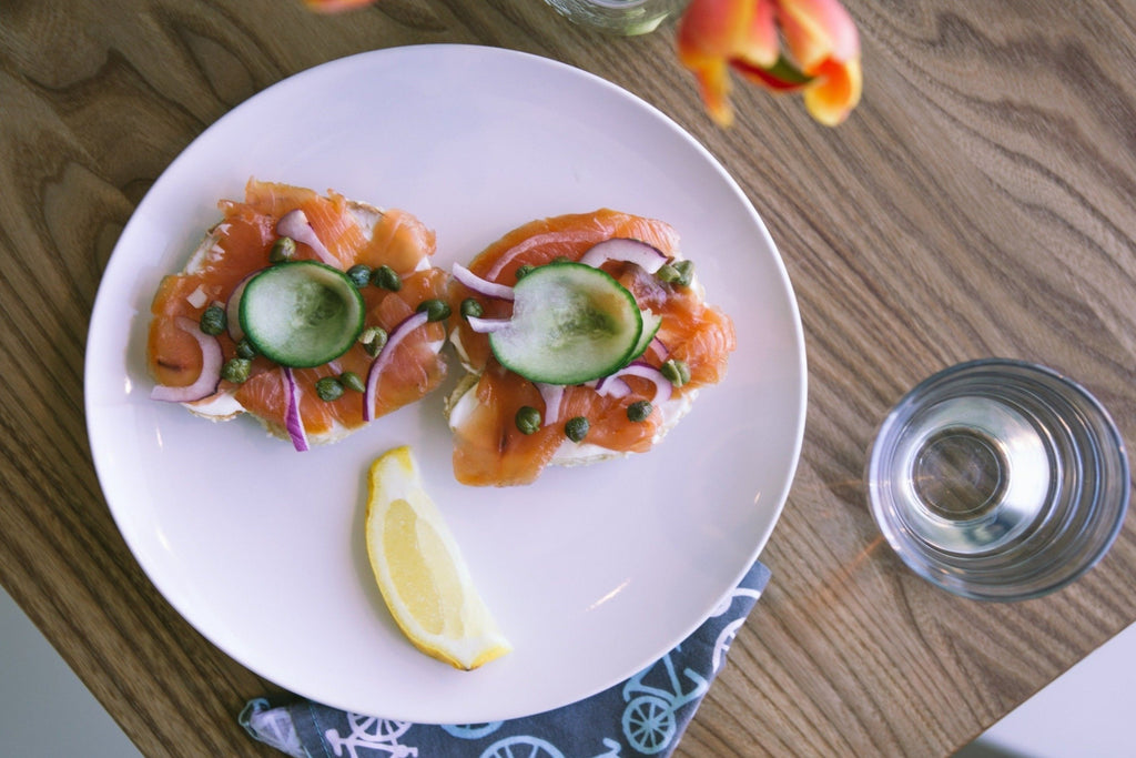Salmon and lox with lemon slice on a white plate on a brown wooden table