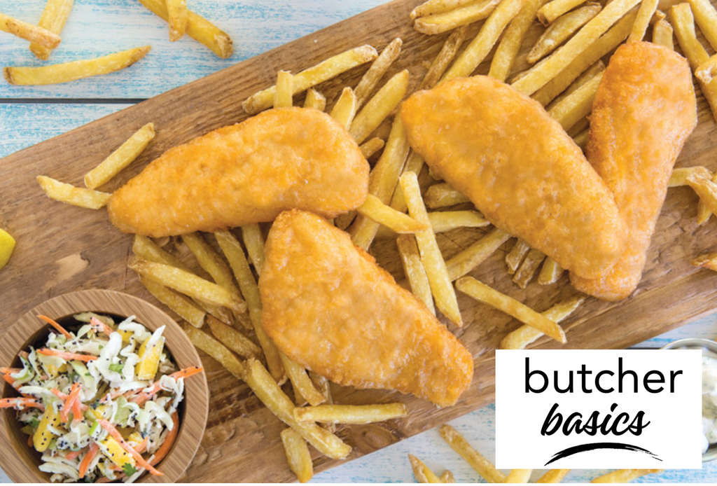 Four Battered cod fillets laying on a bed of French fries with a coleslaw salad on the side. 
