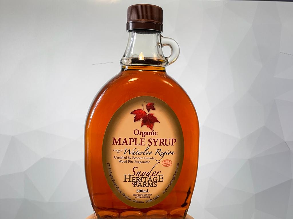 Bottle of pure organic maple syrup against a grey background