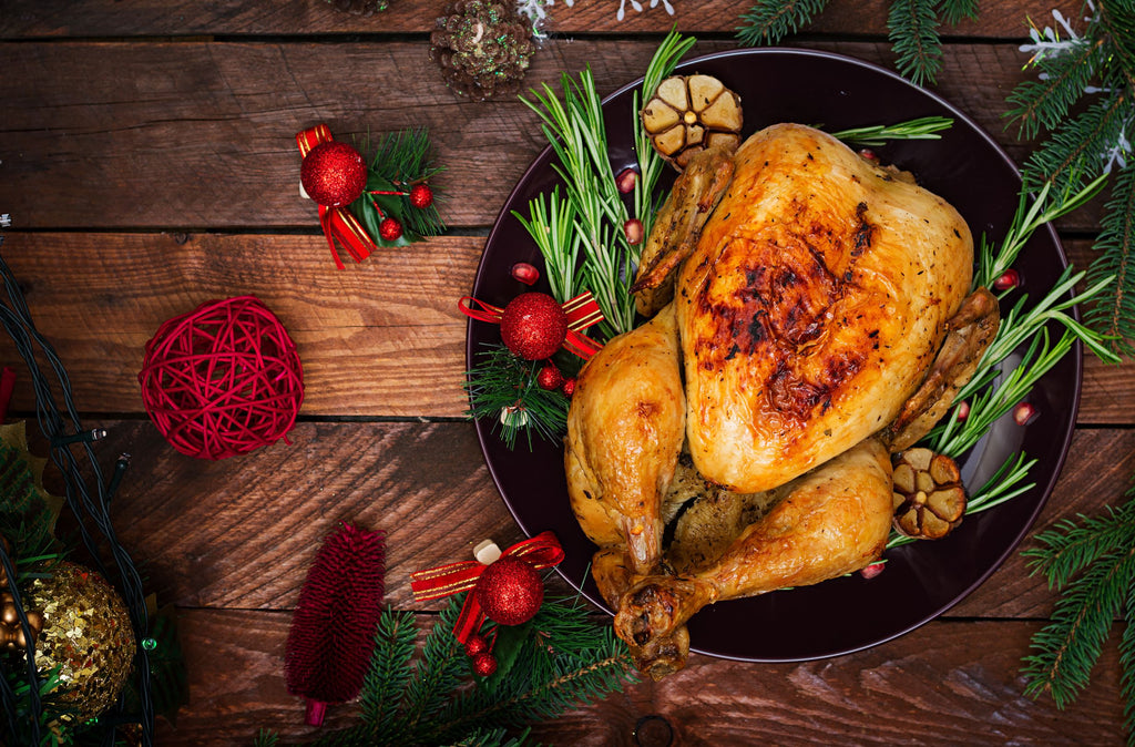 Cooked, golden-brown whole turkey, displayed in a cast iron skillet surrounded by Xmas ornaments